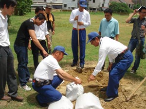 現地の中学校の先生に土のう作りを指導する消防団員の皆さんの写真