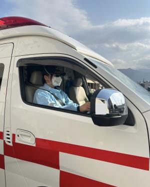 職員がサングラスをかけて救急車を運転している写真です。