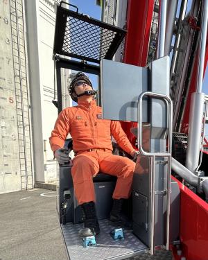 職員がサングラスをかけてはしご車を操作している写真です。