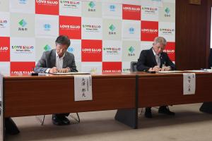 協定書に署名を行う大澤社長、越智市長